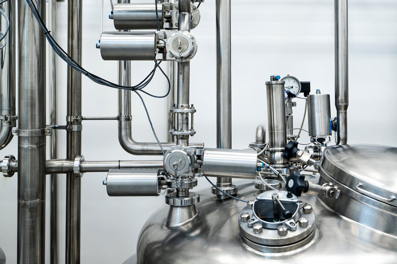 Close-up of stainless steel machinery and pipes in an industrial setting, showcasing modern engineering.