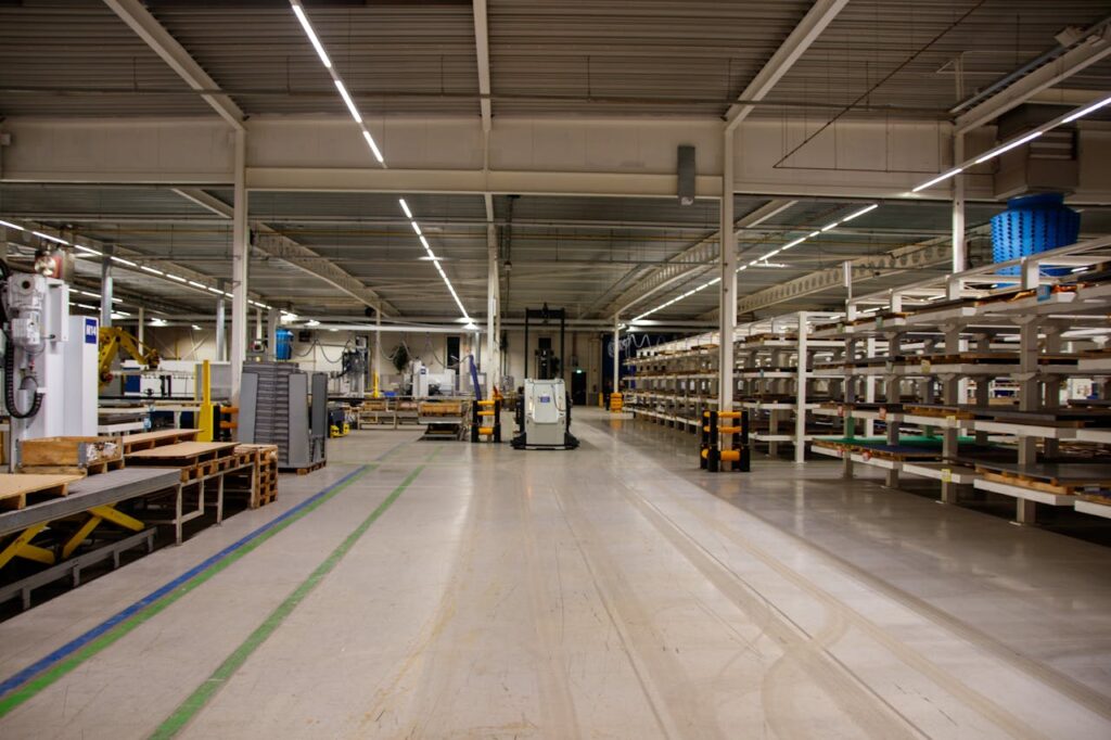 Spacious industrial warehouse interior featuring machinery and storage shelves.